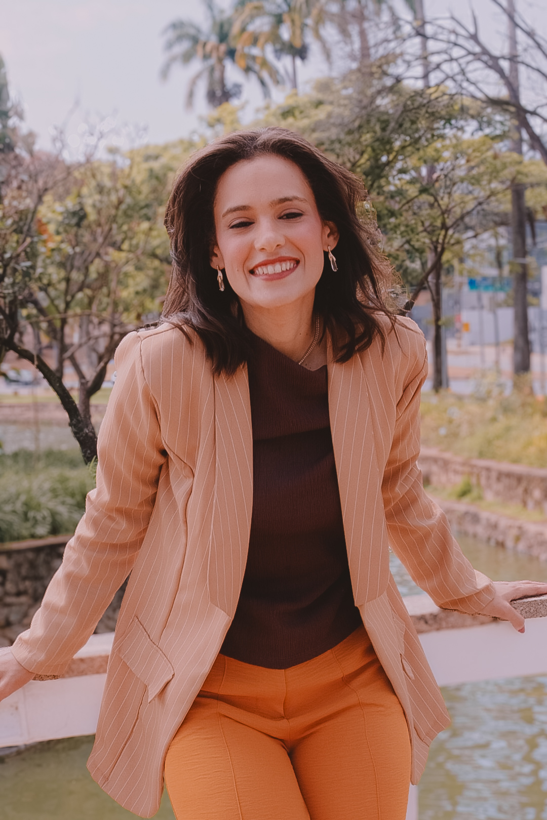 Débora Maia sorrindo em ambiente externo, em atitude acolhedora